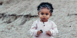 Closeup of Lennox, a toddler with brown skin and curly black hair in half cornrows.